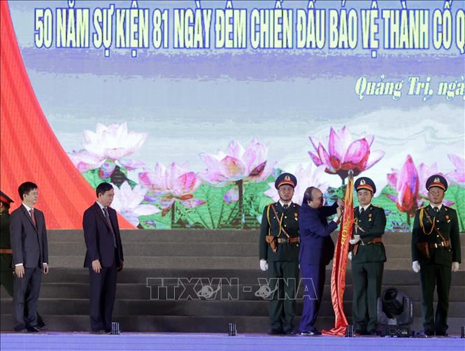 Chủ tịch nước Nguyễn Xuân Phúc gắn Huân chương Hồ Chí Minh lên lá cờ truyền thống của tỉnh Quảng Trị. Ảnh: Thống Nhất/TTXVN