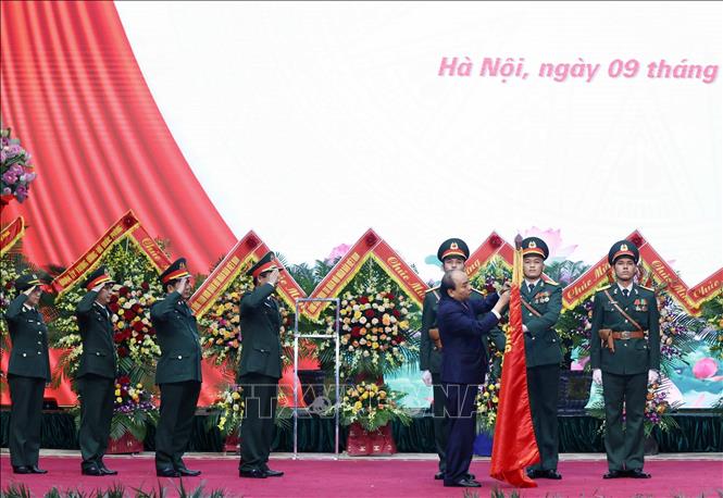 Chủ tịch nước Nguyễn Xuân Phúc gắn Huân chương Bảo vệ Tổ quốc hạng Ba lên lá cờ truyền thống của Binh đoàn 11. Ảnh: Thống Nhất/TTXVN
