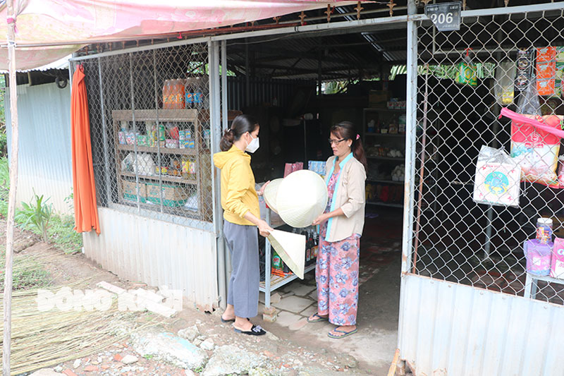 Chị Nguyễn Thị Thu (bìa phải) bên căn nhà tiền chế, thường xuyên bị ngập nước. 