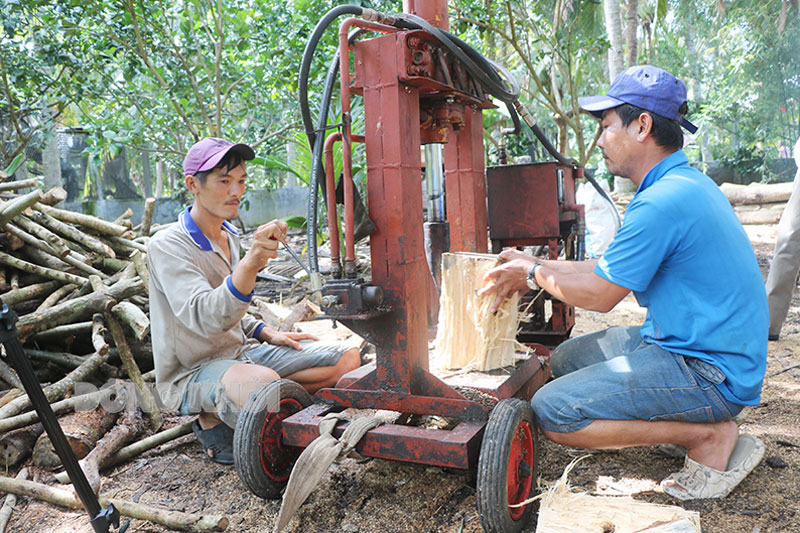 Anh Huỳnh Tuấn Khải (bên trái) nhờ vốn vay cho hộ cận nghèo đã phát triển công việc chẻ củi, bán củi.