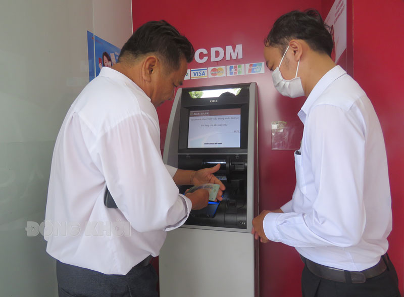 Nhân viên Agribank hướng dẫn khách hàng sử dụng máy Gửi - Rút tiền tự động.