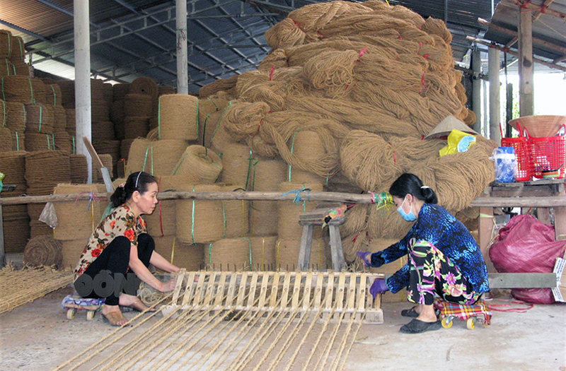 Bà Trần Thị Nga (bên trái) dệt thảm xơ dừa tại cơ sở của em gái ruột thứ 6.