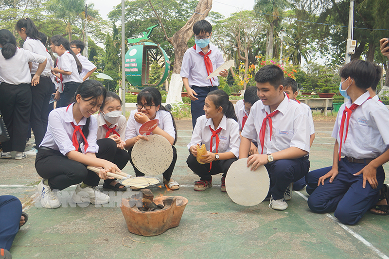 Các em học sinh tham gia trải nghiệm nướng bánh trán, bánh phồng.