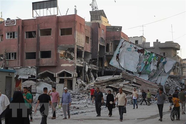 Người dân di chuyển qua những tòa nhà bị phá hủy sau các cuộc không kích của Israel tại Dải Gaza ngày 16-10. (Ảnh: THX/TTXVN)