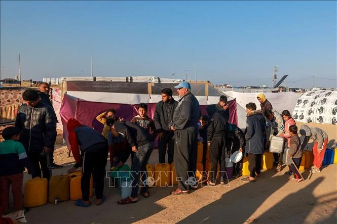 Người tị nạn Palestine xếp hàng lấy nước sinh hoạt tại khu lều tạm ở Dải Gaza ngày 16-1-2024. Ảnh: AFP/TTXVN