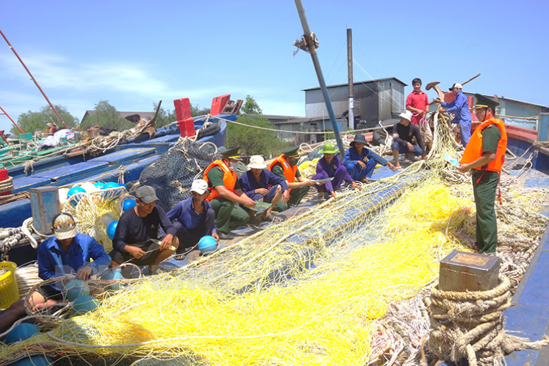 Cán bộ Đồn Biên phòng Hàm Luông tuyên truyền cho ngư dân chấp hành pháp luật khi ra khơi bám biển. Ảnh: Phương Khánh